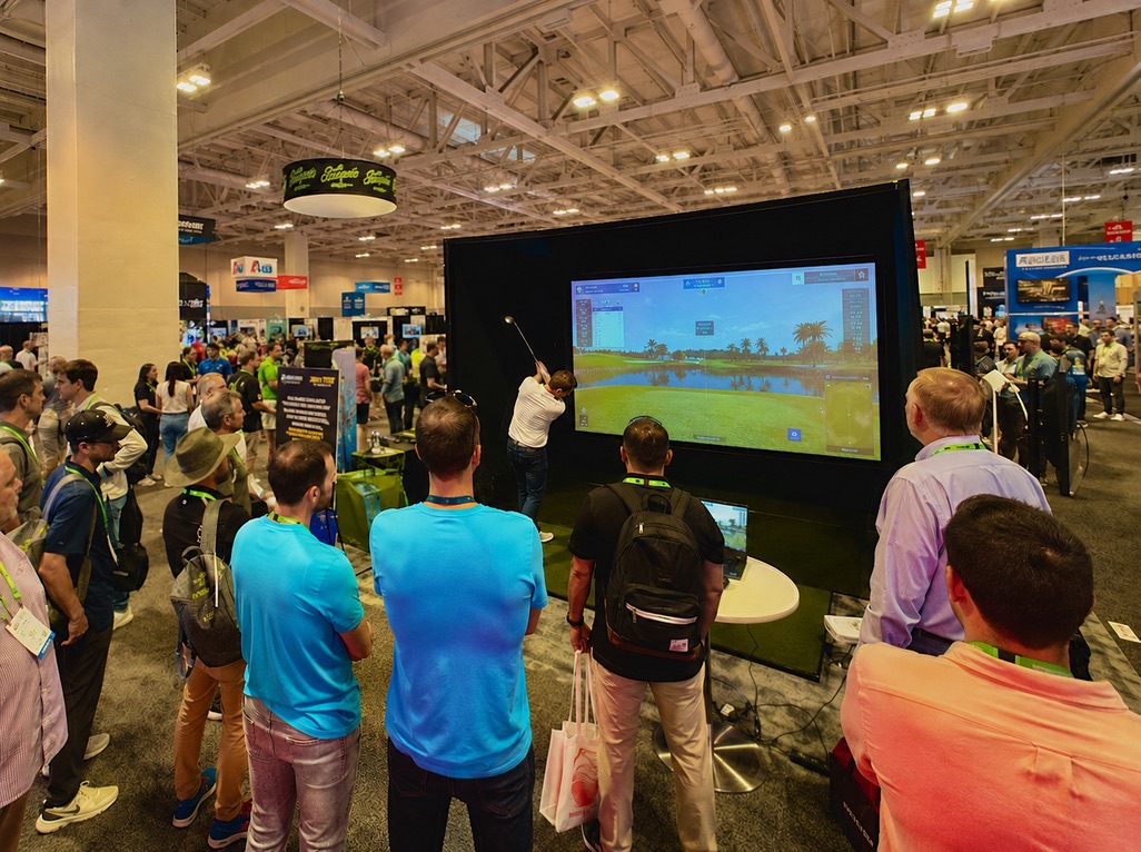 Iron Tee golf simulator setup at a busy convention and trade show floor